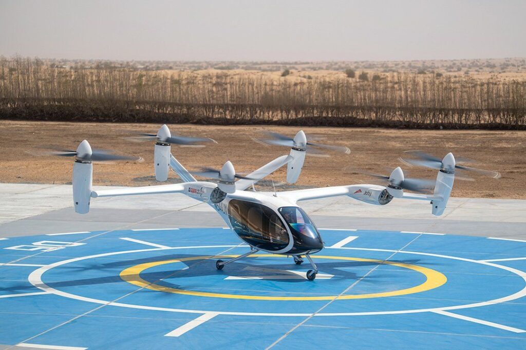 Futuristic Drone Like Air Taxi On Helipad Surrounded By Desert Landscape